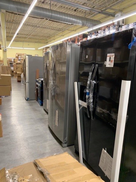Warehouse aisle stocked with rows of major appliances ready for wholesale pickup